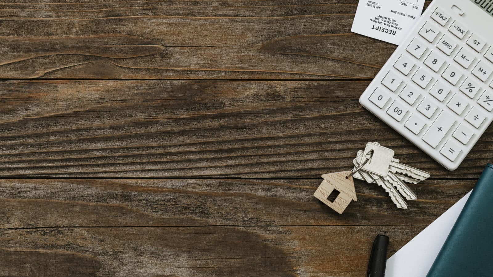 Calculatrice et documents immobiliers sur une table en bois pour fixer un loyer