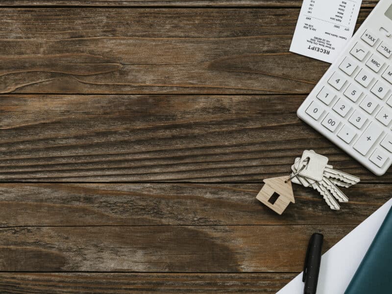 Calculatrice et documents immobiliers sur une table en bois pour fixer un loyer