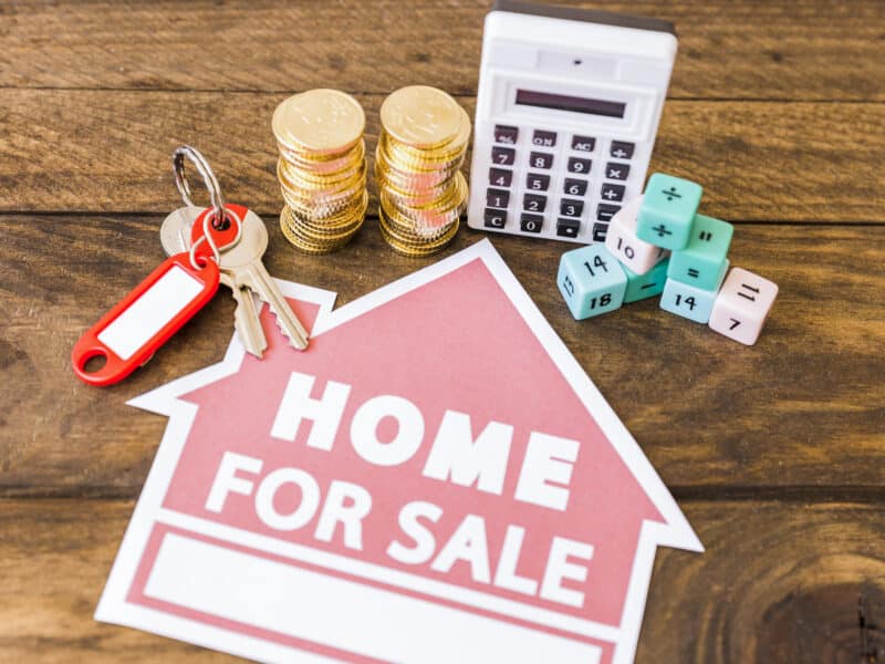Calculatrice, pièces et clé illustrant le calcul de la plus-value immobilière LMNP