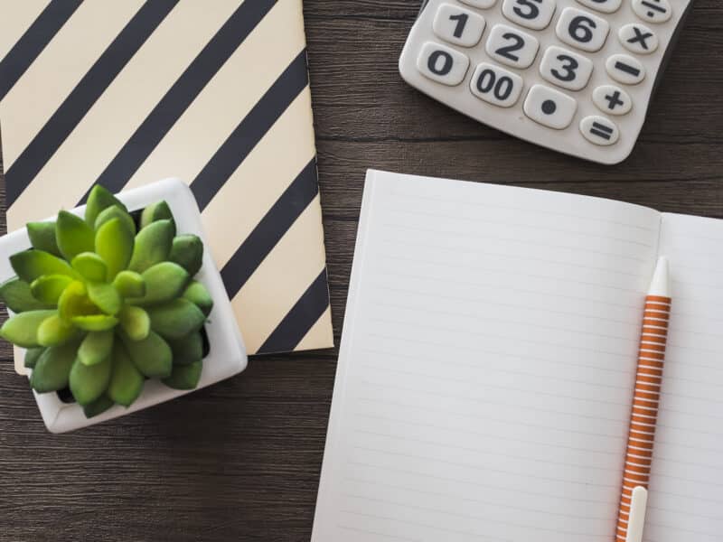 Calculatrice, carnet et stylo sur un bureau en bois, vue de dessus, comptabilité d'une location meublée