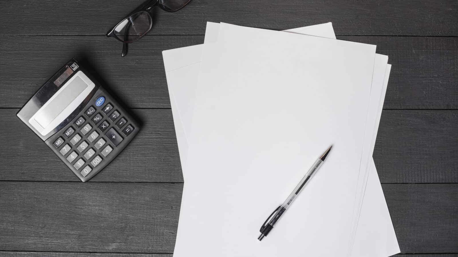 Stylo posé sur des formulaires papier avec calculatrice, préparation de la déclaration 2042 C-PRO