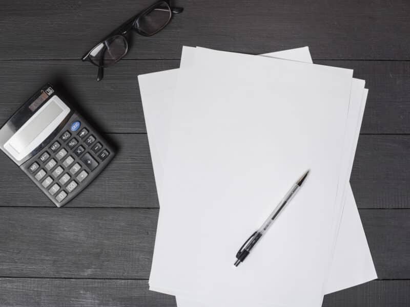 Stylo posé sur des formulaires papier avec calculatrice, préparation de la déclaration 2042 C-PRO