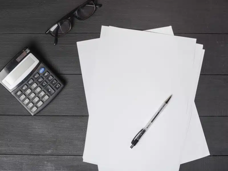 Stylo posé sur des formulaires papier avec calculatrice, préparation de la déclaration 2042 C-PRO