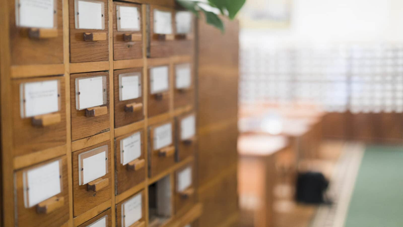 Anciens tiroirs de fiches d'archives en bois, évoquant le formulaire papier P0i supprimé depuis 2023