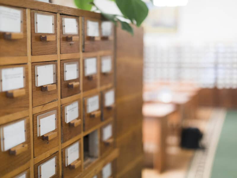 Anciens tiroirs de fiches d'archives en bois, évoquant le formulaire papier P0i supprimé depuis 2023