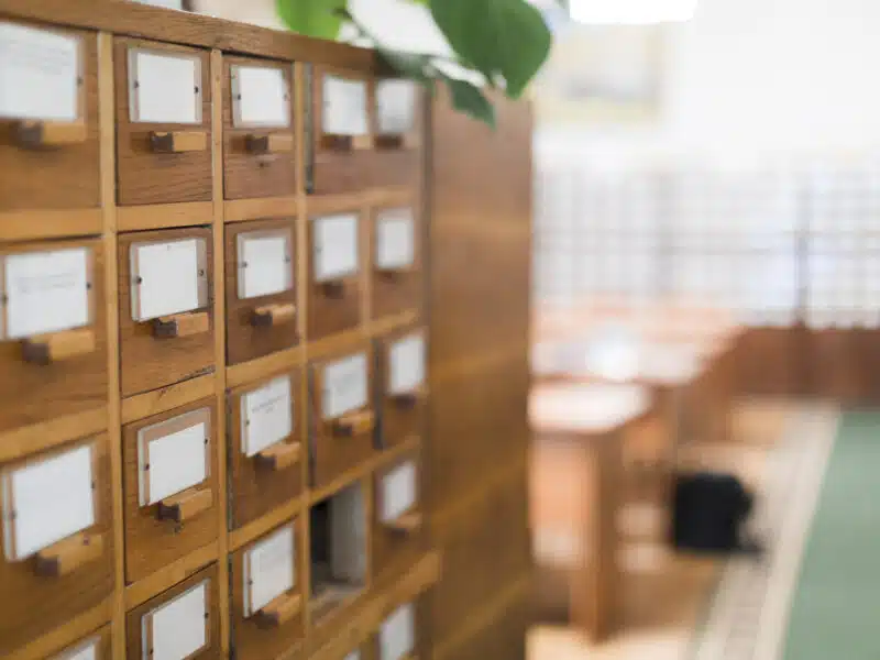 Anciens tiroirs de fiches d'archives en bois, évoquant le formulaire papier P0i supprimé depuis 2023