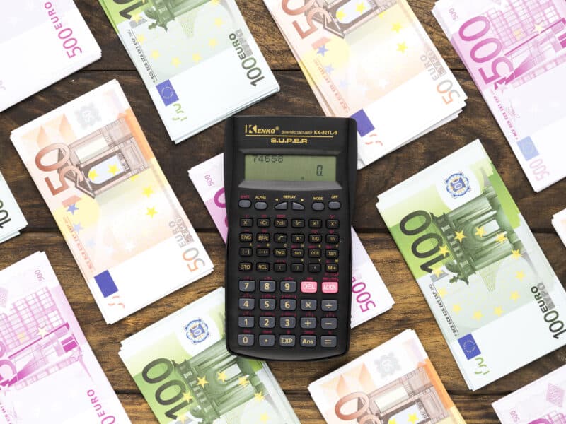 Calculatrice posée sur des billets en euros, illustrant le calcul des prélèvements sociaux et cotisations Urssaf en LMNP