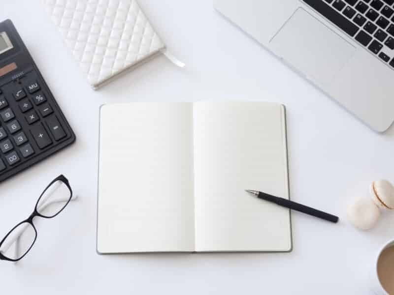 Bureau vu de dessus avec carnet ouvert et stylo, tenue de la comptabilité d'une location meublée soi-même