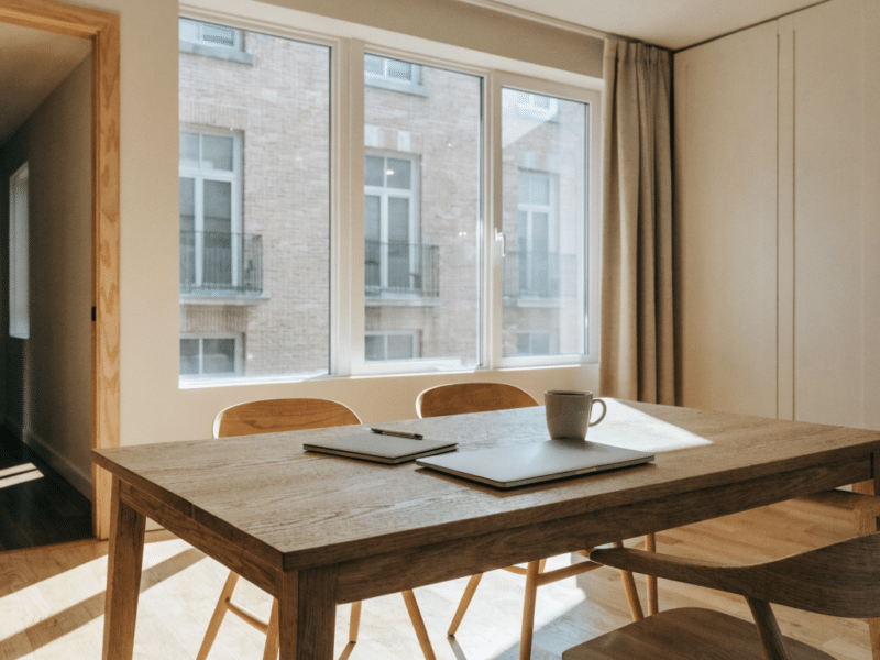 Table de salle à manger avec ordinateur portable et tasse de café dans un meublé lumineux